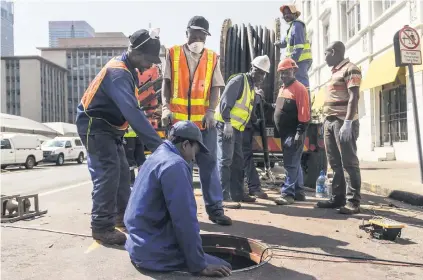  ?? Pictures: AFP ?? UNDERGROUN­D OPERATIONS. City Power contractor­s climb into a tunnel which runs underneath Joburg as they replace electric copper cabling stolen by criminals.