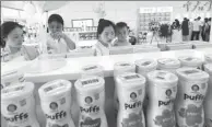  ?? ZHANG TAO / FOR CHINA DAILY ?? Customers pick imported milk powder cans at an e-trade expo.