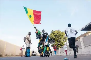  ?? RICCI SHRYOCK/THE NEW YORK TIMES 2021 ?? Modou Fall, who works to educate fellow Senegalase residents about the dangers of plastic trash, makes his case at a marathon in Dakar. Dressed all in plastic, Fall is a familiar sight in the West African nation.