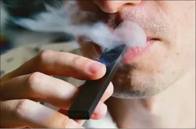  ?? Eva Hambach / AFP/Getty Images ?? An illustrati­on of a man exhaling smoke from an electronic cigarette.