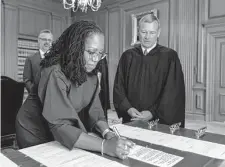  ?? Fred Schilling/Associated Press ?? New Supreme Court Justice Ketanji Brown Jackson signs the oaths of office as Chief Justice John Roberts looks on.