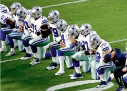  ??  ?? The Dallas Cowboys team go down on their knees during the national anthem prior to an NFL game against the Arizona Cardinals in Glendale, USA. —