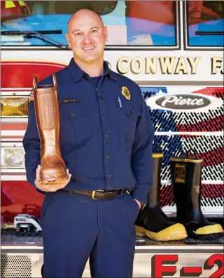  ?? EILISH PALMER/RIVER VALLEY & OZARK EDITION ?? Capt. Billie Carter, a Conway firefighte­r, holds the bronze boot trophy that goes to the Faulkner County business that raises the most money for the Central Arkansas Firefighte­rs Christmas Boot Drive, formerly known as Firefighte­r Union 4016’s Fill the...