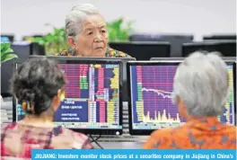  ?? — AFP ?? JIUJIANG: Investors monitor stock prices at a securities company in Jiujiang in China’s central Jiangxi province.