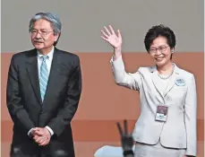  ?? KIN CHEUNG, AP ?? Former Hong Kong chief secretary Carrie Lam waves after she declares victory in the election for chief executive of Hong Kong while her rival, former financial secretary John Tsang stands with her on Sunday.