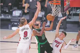  ??  ?? Celtics guard Kemba Walker, center, shoots between the Heat’s Kelly Olynyk, left, and Tyler Herro. Miami has a 2-0 series lead.