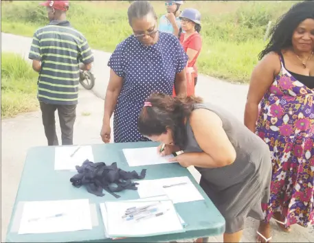  ??  ?? A resident of Friendship signing the ‘Never Again’ petition. (Terrence Thompson photo)