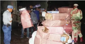  ?? ?? Some of the seven cigarette smugglers load their contraband into a military truck under the guard of security forces after they were intercepte­d at an illegal crossing point near Nottingham Estate west of Beitbridge along the Limpopo River on Saturday night