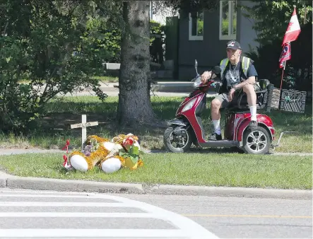  ?? JIM WELLS ?? Andy Ethier pays his respects Wednesday at a roadside memorial on Acadia Dr S.E. dedicated to Hilda Klemmer, who was fatally struck by a truck Tuesday. Ethier said he would often see Klemmer and her granddaugh­ter, who was injured in the incident, when...