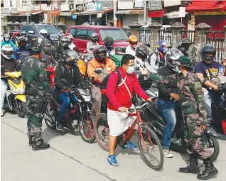  ??  ?? STOP-CHECK-GO ... Soldiers checking road users at a checkpoint in Las Pinas, Manila yesterday to ensure strict compliance of procedures to stop the spread of Covid-19. – EPAPIX