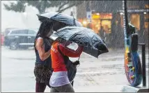  ?? AMANDA VOISARD / AMERICAN-STATESMAN ?? Justine Gilcrease (left) and Jardine Libaire battle heavy rain Friday as they make their way to an Austin exercise class. Rain began pummeling the city in the morning.