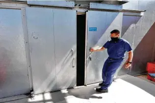  ?? Matt York / Associated Press ?? Pima County Medical Examiner Dr. Greg Hess opens an overflow body storage cooler in July in Tucson, Ariz. A sweltering summer led to a record number of border-crossers found dead.