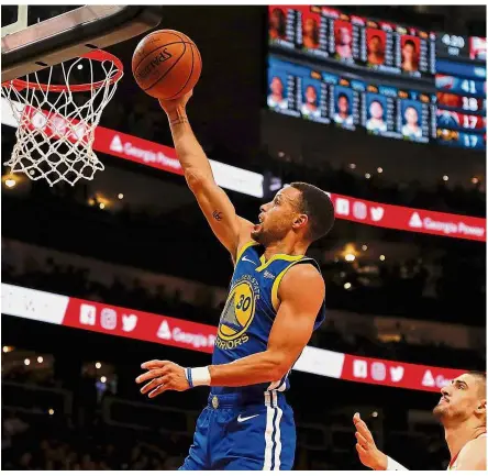  ??  ?? On target: Stephen Curry (left) of the Golden State Warriors lays in a basket during the NBA match against the Atlanta Hawks at the State Farm Arena on Monday. — AFP