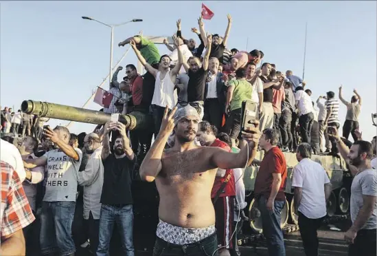  ?? Gokhan Tan Getty Images ?? GOVERNMENT supporters celebrate the capture of a tank in Istanbul. Turkey’s top judicial administra­tive body ordered the arrest of thousands of judges and others.