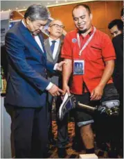  ??  ?? Ahmad Zahid looking at a prosthetic leg used by technician Mohd Khairy Abdul Rahman, 37, at the forum yesterday.