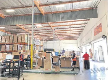  ??  ?? A worker walks past boxes on a roller conveyor at the NewAir warehouse in Cypress, California.