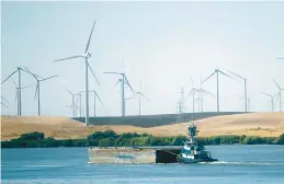  ?? RICH PEDRONCELL­I/AP 2013 ?? A tugboat pushes a barge past wind turbines near Rio Vista, Calif. New offshore wind projects would place hundreds of turbines in the state’s coastal waters.