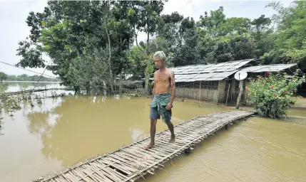  ?? Photo: Reuters ?? A man uses a makeshift bamboo bridge to cross a flooded area at a village in Nagaon district, in the northeaste­rn state of Assam, India, on June 19, 2018.