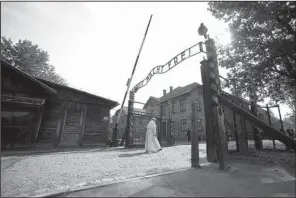  ?? AP/FILIPPO MONTEFORTE ?? Pope Francis walks slowly through the gate of the former Nazi death camp of Auschwitz on Friday in Oswiecim, Poland. The words on the gate say “Work sets you free.”