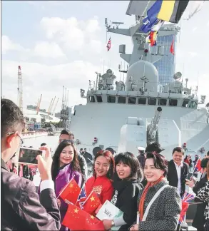  ?? ZHANG PING / CHINA NEWS SERVICE ?? Tourists pose for pictures in front of a Chinese naval vessel docked at London’s Canary Wharf on Tuesday. The 26th Escort Task Group of the People’s Liberation Army Navy arrived in the UK capital on Monday, marking the first visit of the Navy to the...