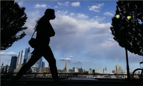  ?? FRANK FRANKLIN II — THE ASSOCIATED PRESS ?? A woman wearing a protective mask walks along Sinatra Drive North in view of midtown Manhattan, Thursday, May 7, 2020, in Hoboken, N.J.