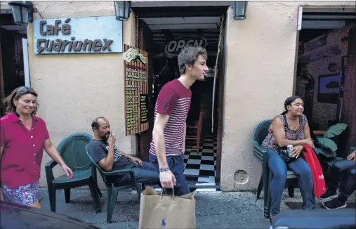  ?? AP PHOTO ?? German tourists Nikola Sheienssen and her son Stephan Julian walk past the Guarionex Cafe, one month after the passage of Hurricane Maria in Old San Juan, Puerto Rico. The family from Kiel, Germany said they had some trouble finding a hotel and were...