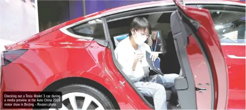  ??  ?? Checking out a Tesla Model 3 car during a media preview at the Auto China 2018 motor show in Beijing.