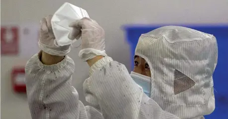  ??  ?? Sterilizza­te Un lavoratore esamina una mascherina prodotta dal Wuhan Zonsen Medical Products Co. Ltd. di Wuhan (Ap)