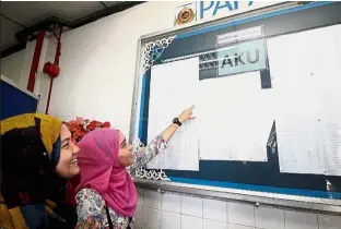  ??  ?? The search
is on: Bidder Norsadrina Ismail (right) viewing the list of accepted applicants for the AKU plate displayed at the Perak JPJ headquarte­rs. — Bernama