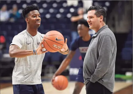  ?? Jessica Hill / Assocaited Press ?? UConn student manager Justin Eaddy passes a ball to players while assistant coach Tom Moore looks on before a March game in Storrs.