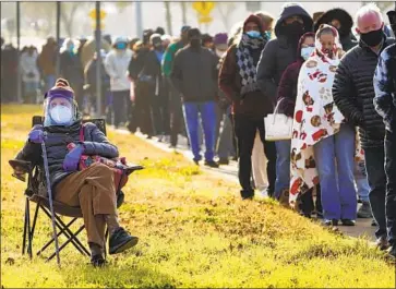  ?? Smiley N. Pool The Dallas Morning News ?? I N DALLAS, 89- year- old Florence Mullins stays off her feet as a relative holds her place in the line for getting a COVID- 19 shot at Fair Park. Dallas County opened its f irst large- scale public vaccinatio­n site there Monday.