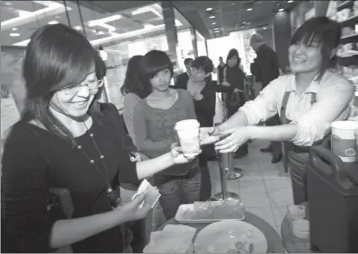  ?? AP ?? A Starbucks staff member hands out free coffee to customers at an event to mark the 10th anniversar­y of Starbucks’ launch in China, at the company’s original outlet in Beijing.