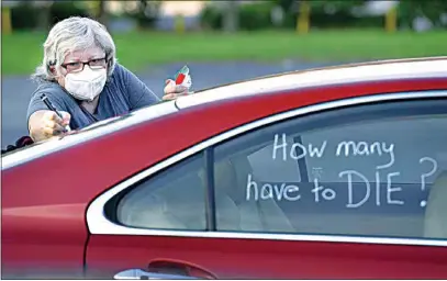  ?? BOB SELF / THE FLORIDA TIMES-UNION VIA AP ?? Registered nurse Laure Hale writes on her car Tuesday as she is prepared to take part in a motorcade protest to the Duval County School Board building in Jacksonvil­le, Fla. Duval County teachers and their supporters gathered in a parking lot before they drove to the Duval County School Board Building and protest plans of starting the upcoming school year with the rate of COVID-19 infections hitting record rates in Jacksonvil­le.