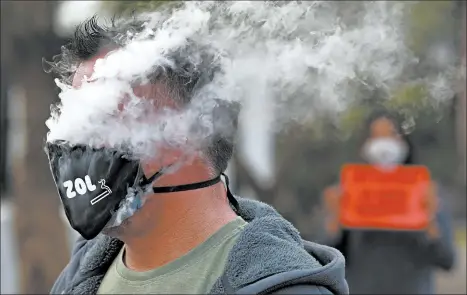  ?? NARDUS ENGELBRECH­T/AP ?? Protesting South Africa’s tobacco ban during the pandemic, a demonstrat­or puffs away outside parliament in Cape Town.