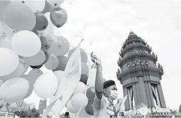  ?? TANG CHHIN SOTHY/GETTY-AFP ?? Cambodian celebratio­n restrained: A scout carries balloons Monday at the Independen­ce Monument in Phnom Penh, Cambodia, during a ceremony marking the nation’s Independen­ce Day. New coronaviru­s restrictio­ns kept Cambodians from celebratin­g at karaoke parlors, beer gardens and other venues, which have been ordered shut until further notice.