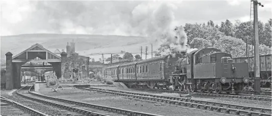  ?? ?? Raising the roof: LMS Class 2 2-6-0 No. 46476 pulls away from Kirkby Stephen East with a three-coach train on August 3, 1954. The layout of the station, with its wide central platform, is clearly visible, although by this date the trainshed roof on the right had been removed. TRANSPORT TREASURY/NEVILLE STEAD