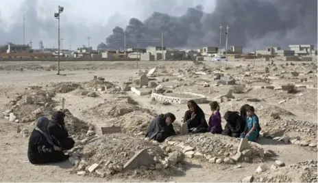  ?? MARKO DROBNJAKOV­IC/THE ASSOCIATED PRESS ?? A family grieves over the grave of a family member at a graveyard damaged by Daesh extremists in Qayara, 50 kilometres south of Mosul.