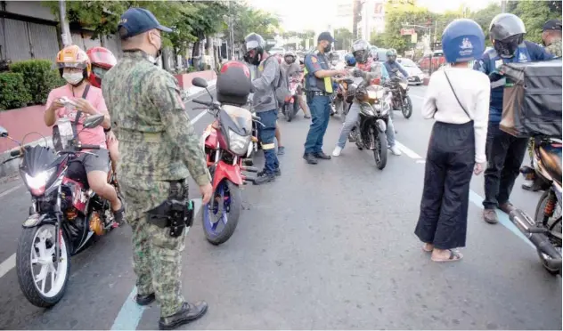  ?? Agence France-presse ?? ↑
Police officers check documents of motorists at a check point in Manila City on Sunday.