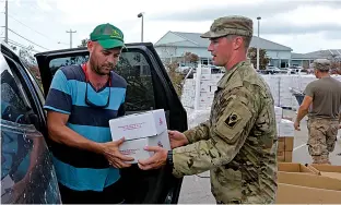  ?? Associated Press ?? n A member of the National Guard hands over boxes of food to Patrick Garvey in the aftermath of Hurricane Irma on Thursday in Big Pine Key, Fla.