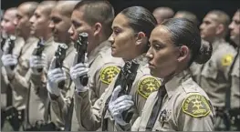  ?? ?? YADIRA FERNANDEZ, front, and other recruits stand ready for weapons inspection during their graduation ceremony at East Los Angeles College.