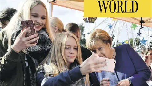  ?? JOHN MACDOUGALL / AFP / GETTY IMAGES ?? German Chancellor Angela Merkel poses for a selfie at a town fair in Stralsund this month. After 12 years in power, Merkel is poised to claim a fourth four-year term in Sunday’s vote.