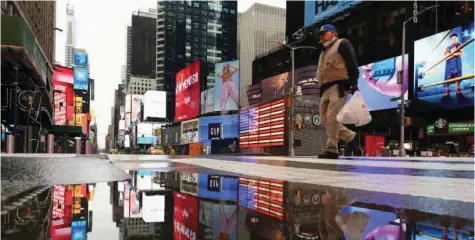  ?? — AFP ?? A man crosses the street at a nearly empty Times Square on April 09, 2020 in New York City.