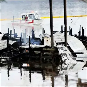  ?? ASSOCIATED PRESS ?? People on a boat patrol near the charred remains of a dock following a fatal fire at a Tennessee River marina in Scottsboro, Ala., Monday.