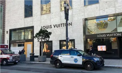  ?? Photograph: Danielle Echeverria/AP ?? A police car is parked outside the Louis Vuitton store in San Francisco’s Union Square, the site of a recent mass theft.