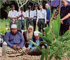  ?? (Foto Mikail ONG/BH) ?? Ahli keluarga, termasuk ibu dan ayah serta rakan sekolah di pusara Muhammad Saifullah di Tanah Perkuburan Bayan Lepas, Pulau Pinang.