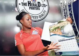  ??  ?? Taina Webb, customer service representa­tive at The Herald Printers Ltd, displays a calendar produced by the company, at Expo Jamaica 2018.