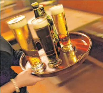  ?? FOTO: MARC TIRL/DPA ?? Eine Bedienung trägt in einem Lokal ein Tablett mit Bier. Etwa 870 000 Minijobber arbeiten im Gastgewerb­e. Sie sind von der Corona-Kurzarbeit­erregelung nicht abgesicher­t.