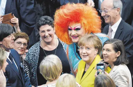  ?? FOTO: DPA ?? Travestiek­ünstlerin Olivia Jones lässt sich mit der Kanzlerin fotografie­ren – oder umgekehrt? Neben dem knalligen Outfit von Olivia Jones wirkte Angela Merkels gelbes Jackett jedenfalls ganz zurückhalt­end. Links Fußball-Nationaltr­ainer Jogi Löw, rechts...