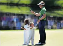  ?? JIM WATSON/GETTY IMAGES ?? Luke Donald takes pictures of daughters Elle and Sophia on the eighth green during Wednesday’s par-3 contest at Augusta.
