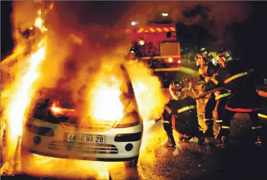 ?? MICHEL SPINGLER/ AP ?? Firefighte­rs douse a burning car in Argenteuil, west of Paris, last night as rioters set hundreds of cars ablaze in the 11th consecutiv­e night of violence in France.